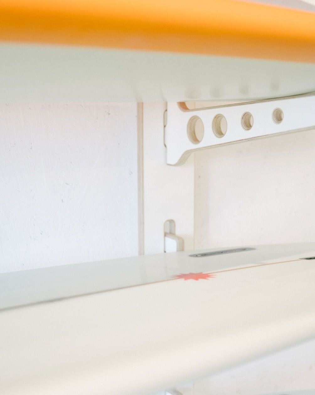 A close-up view of the Surfboard Rack Wall Mount by Timber Grooves, showcasing white surfboards neatly arranged, with one board featuring a red star design.