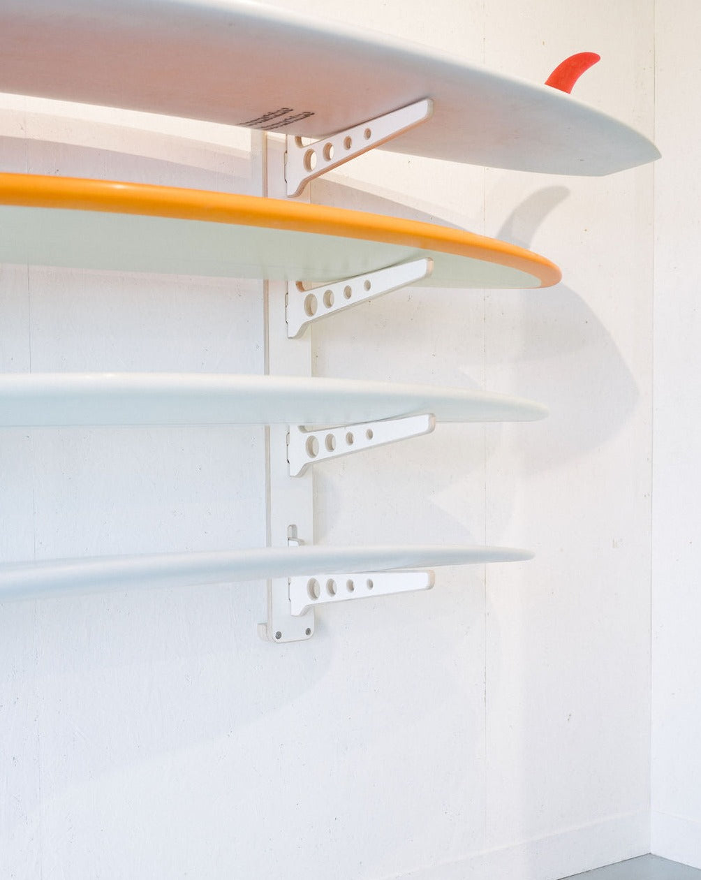Numerous surfboards are neatly organized on a stylish Timber Grooves Surfboard Rack Wall Mount.