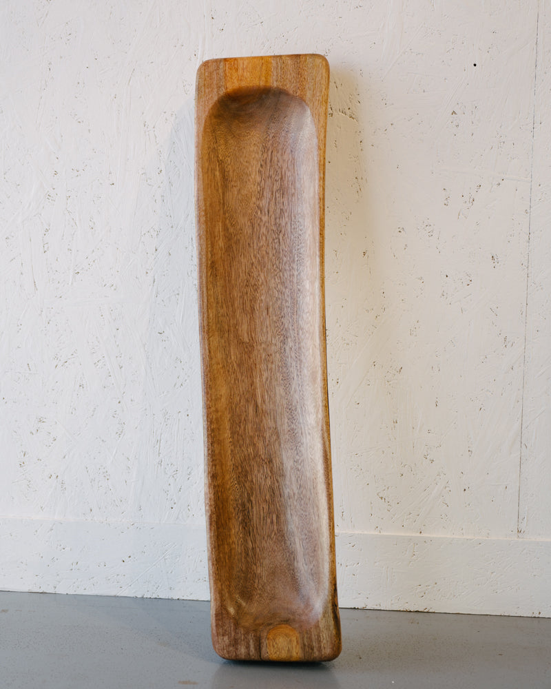 A handcrafted northern hardwood Timber Grooves Centre Piece Bowl stands upright against a white textured wall, showcasing its natural wood grain.