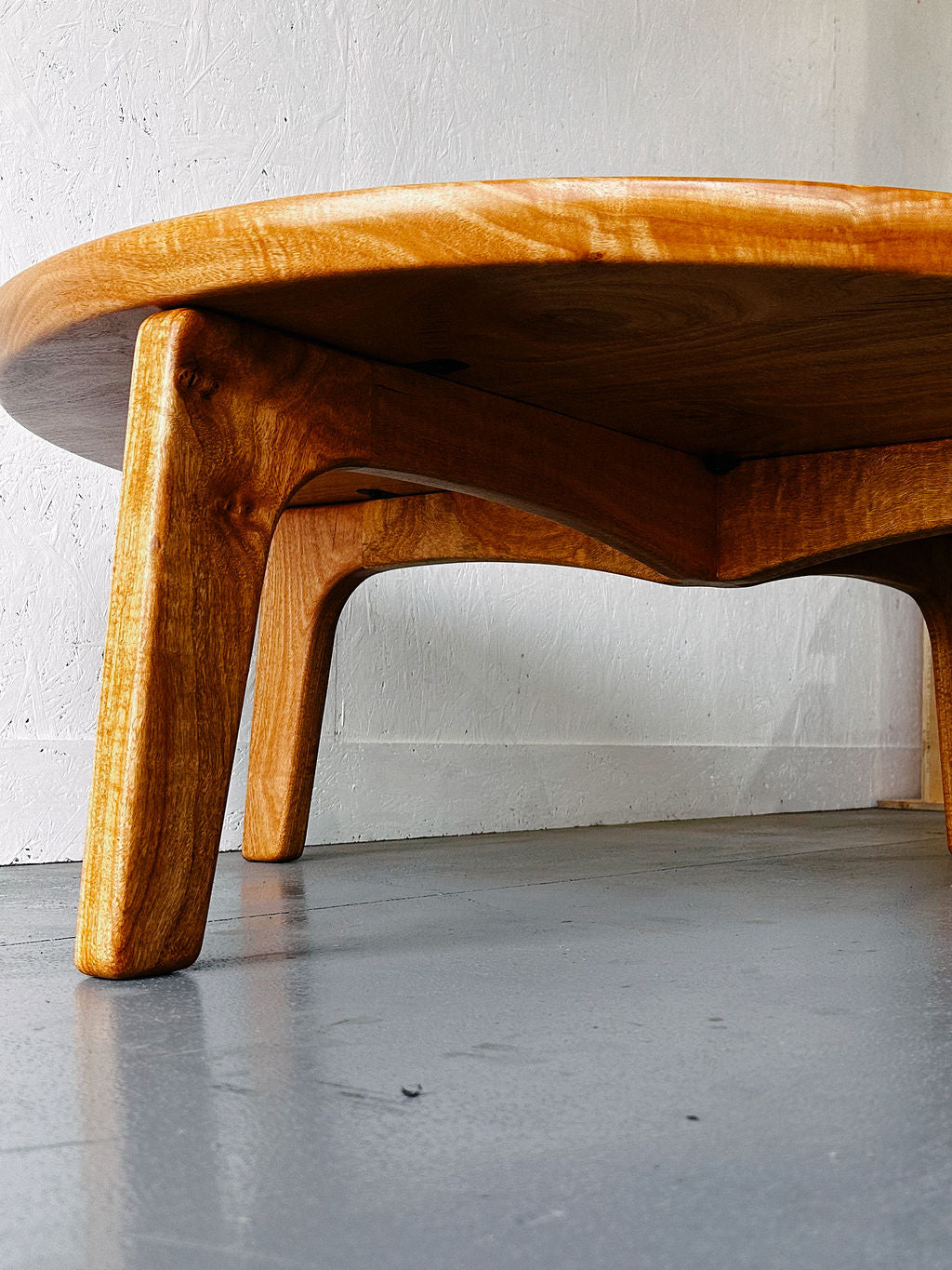 Close-up of a handcrafted Timber Grooves Marri Coffee Table with cylindrical legs and a round top, made from Australian Hardwood, placed on a grey floor with a white wall in the background.