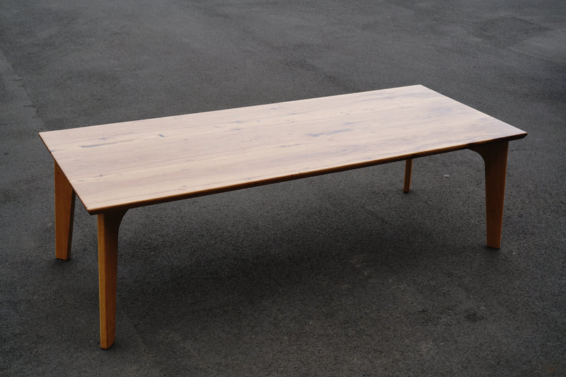 A handcrafted Timber Grooves Marri Dining Table with a smooth surface and four sturdy legs is placed on an asphalt surface, exemplifying luxury dining.