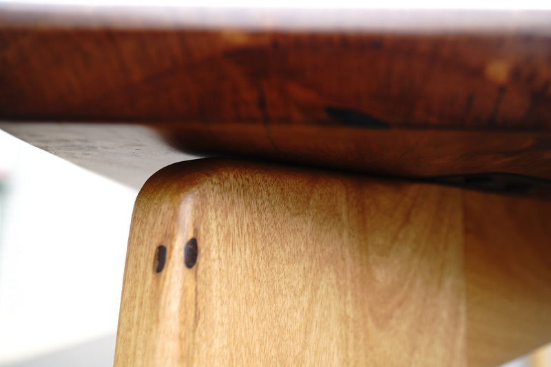 Close-up view of the junction between a wooden table leg and the tabletop, showcasing the wood grain and craftsmanship details of this handcrafted luxury Marri Dining Table by Timber Grooves.