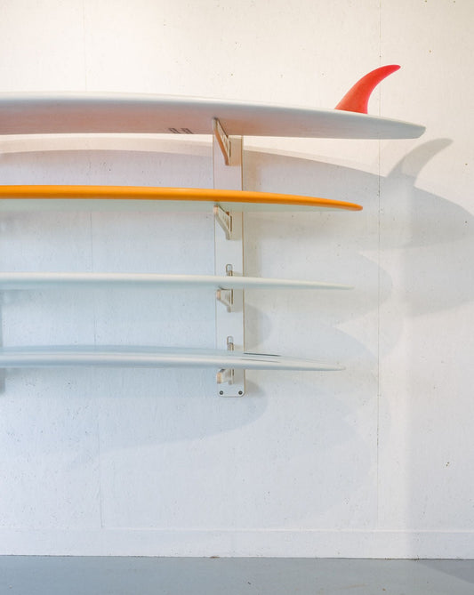 Three surfboards are elegantly showcased on a sleek Timber Grooves Surfboard Rack Wall Mount in a minimalist room.