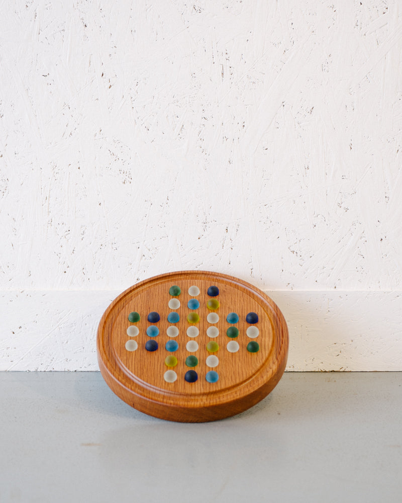 A Solitaire game by Timber Grooves featuring a Chinese checkers pattern with 32 colorful marbles, set against a textured white wall.