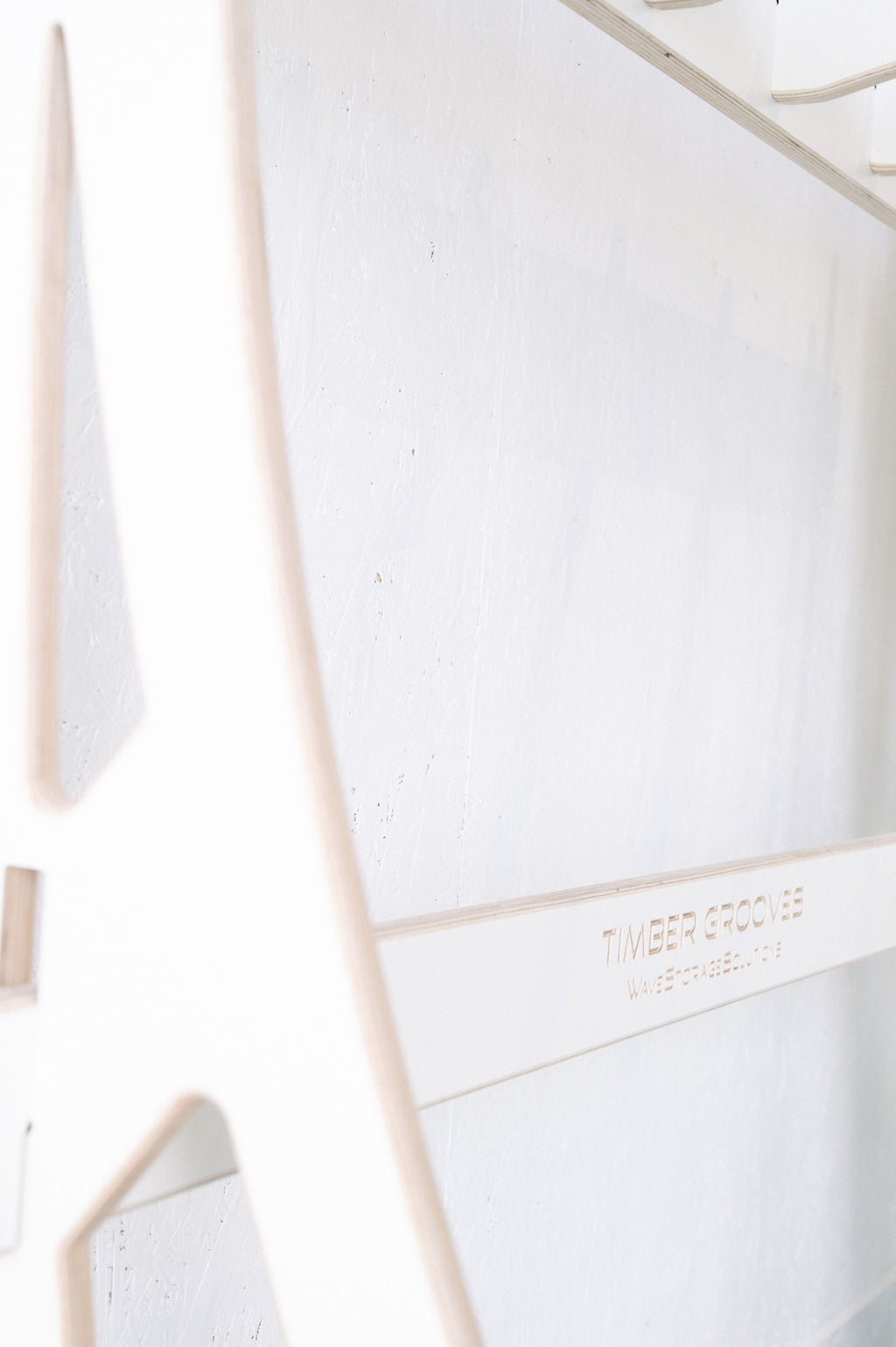 Close-up of a white, textured wooden surface with cutout details featuring the "Timber Grooves" brand name, ideal for wall-mounted versatility and showcasing the Surfboard Rack Freestanding.