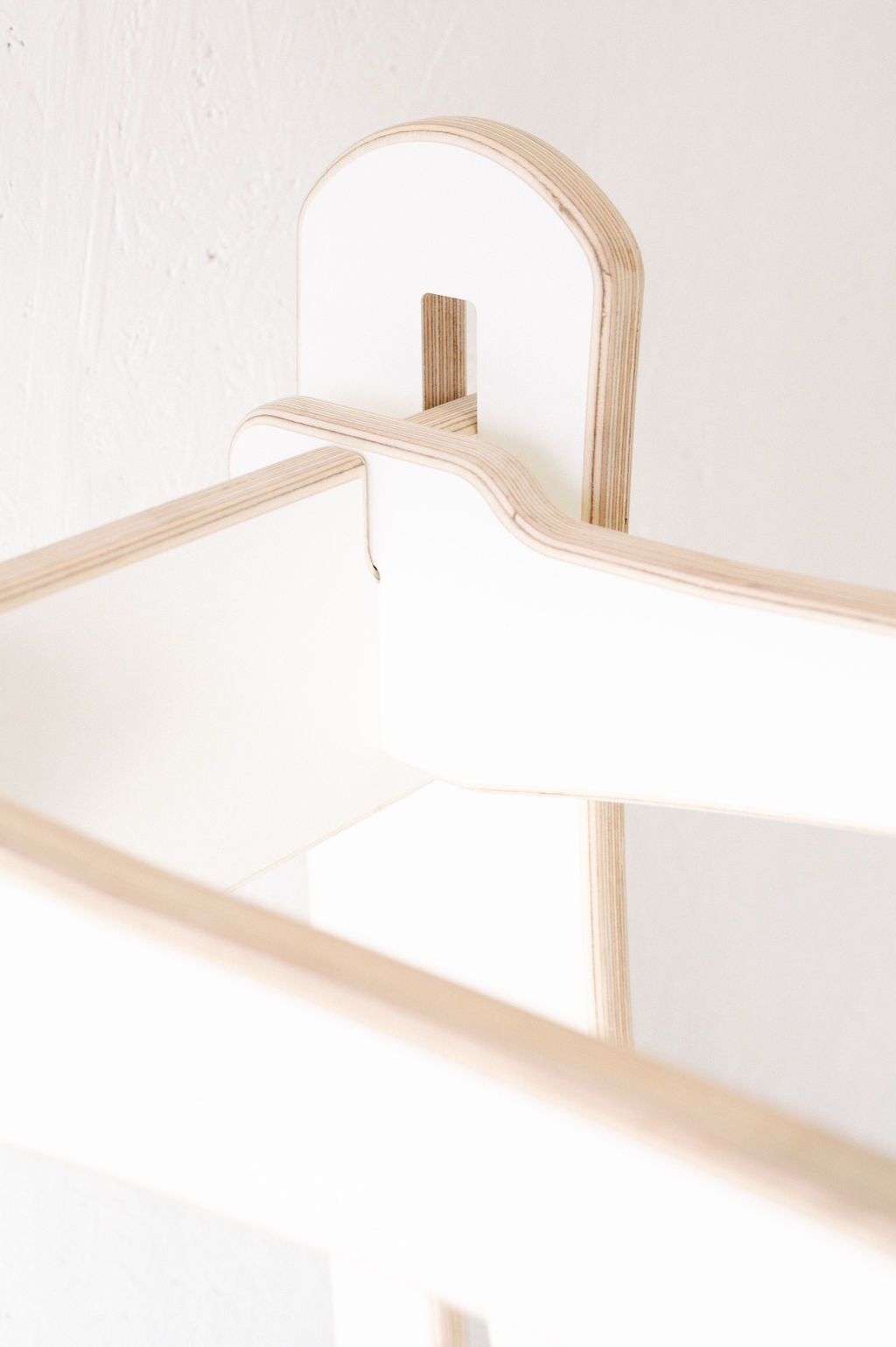 Close-up of a minimalistic wooden and white-painted structure featuring interlocking pieces, set against a white background. Ideal for custom surf rack designs or wall-mounted racks, this versatile piece invites wholesale inquiries for bulk orders. Introducing the Surfboard Rack Freestanding from Timber Grooves.