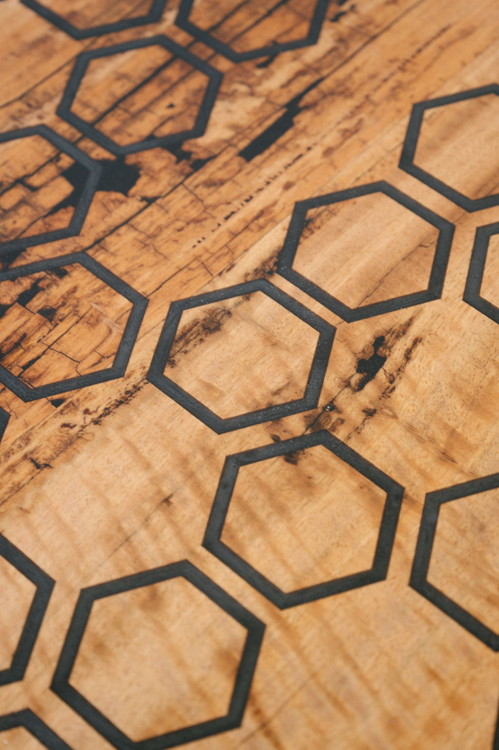 A Marri Coffee Table with a modern design from Timber Grooves showcases black hexagons in a grid-like formation on its natural grain, enhanced by a black resin inlay.