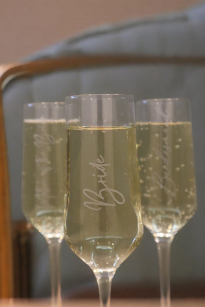 Three Timber Grooves Personalised Champagne Flutes filled with sparkling wine. The center glass features the word "Bride.