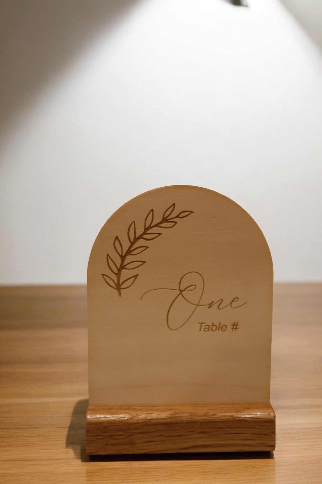 Timber Grooves' Engraved Timber Wedding Table Number showcases the word "One" with a leaf design, infusing rustic charm into your personalized decor.